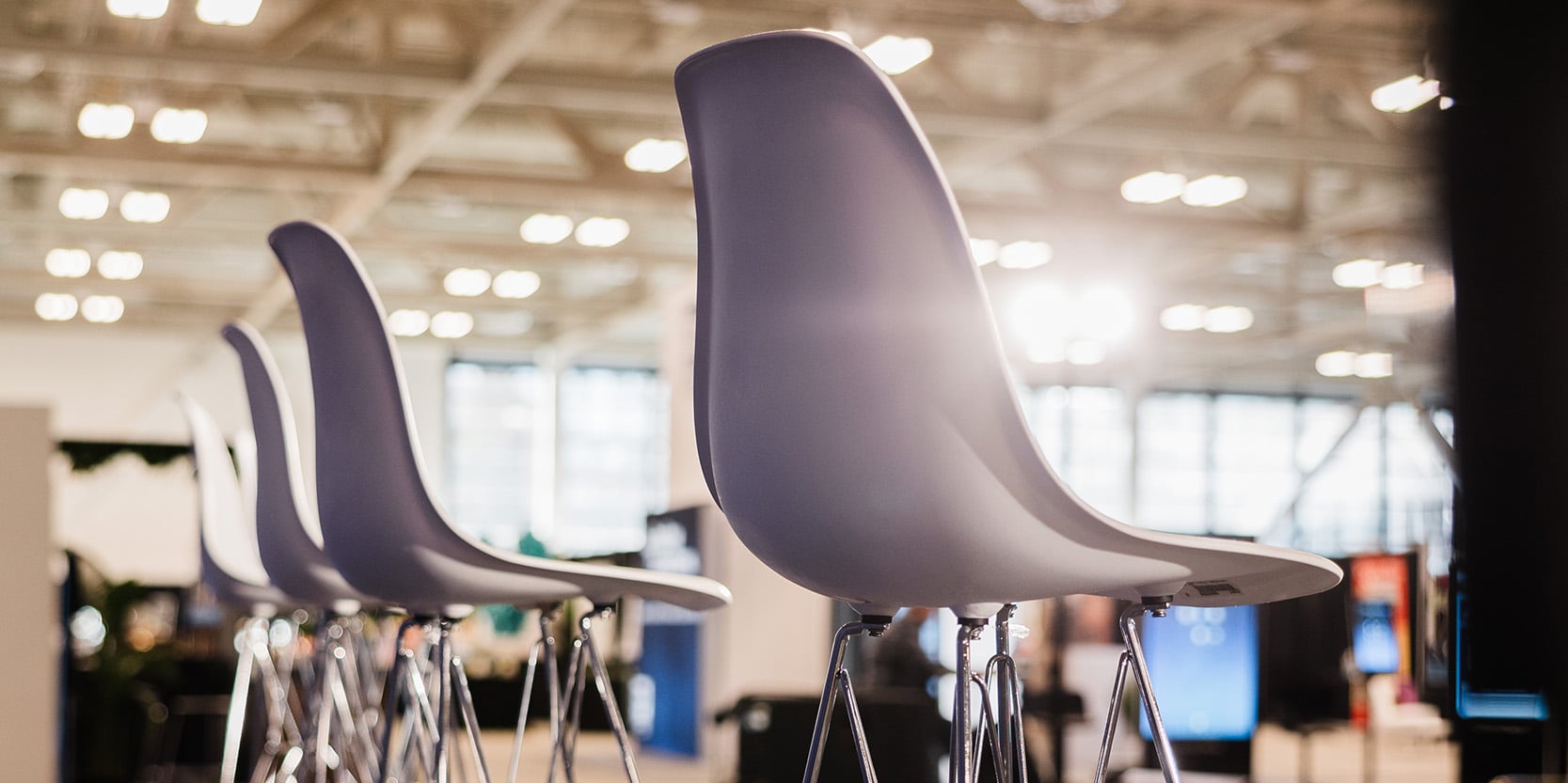small trade show booth with white furniture rentals and employees talking to clients