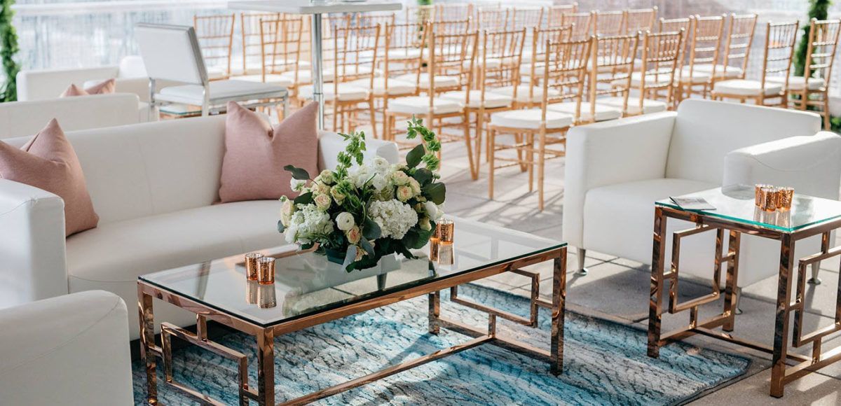 wedding reception area with white soft seating and gold tables