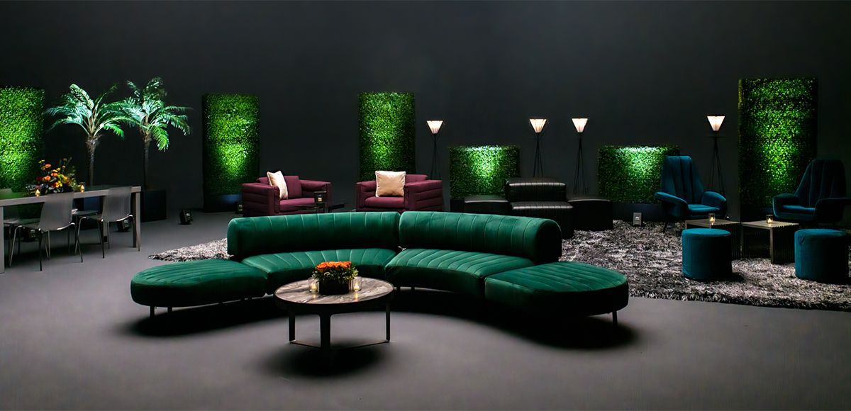 low lit image featuring long, curved emerald green soft seating and various accent chairs