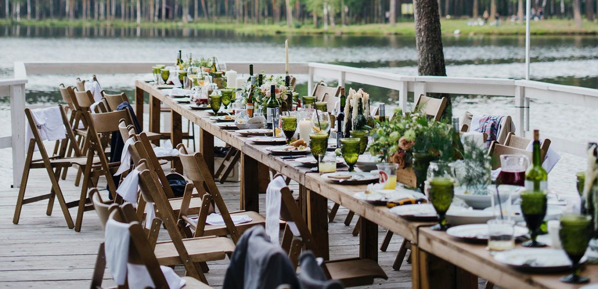Outdoor dining event with rustic tables and chairs.