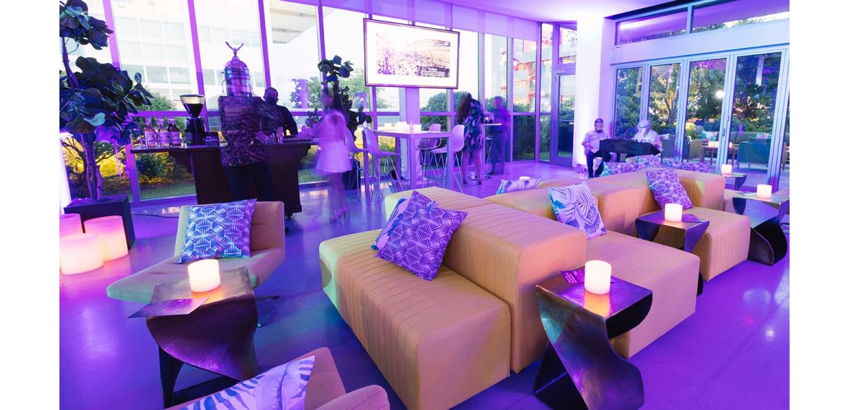 Yellow grouped ottomans with bronze twist tables in low lit purple room. 