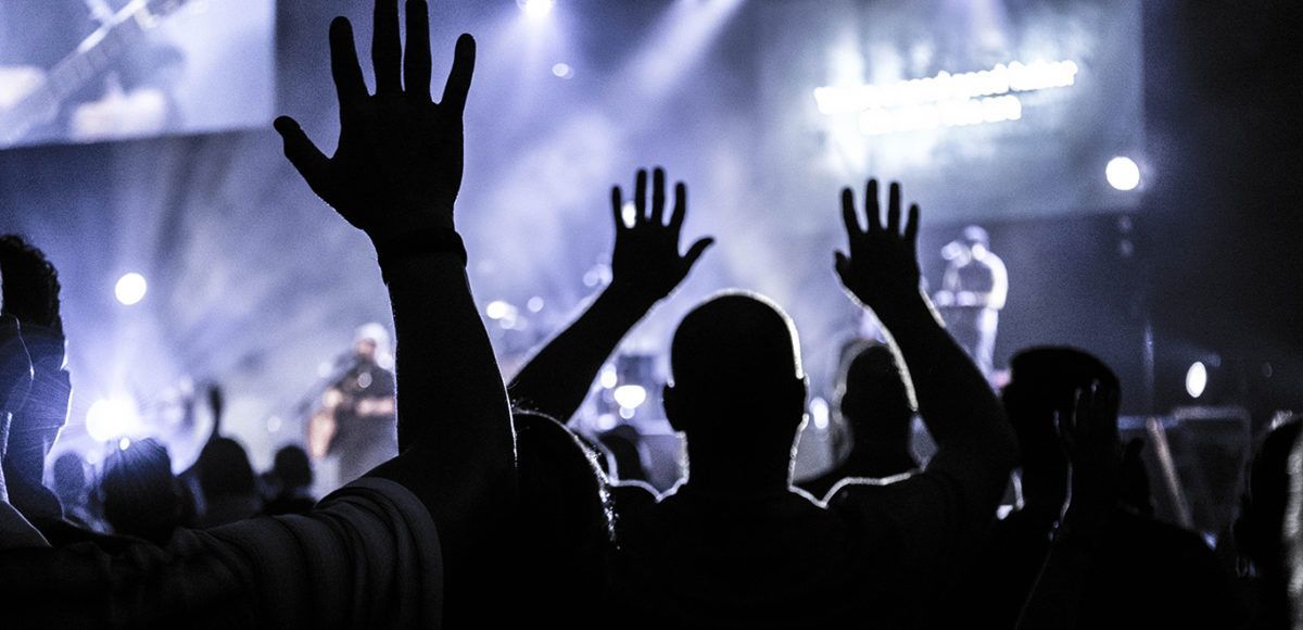 People with hands raised at music festival.