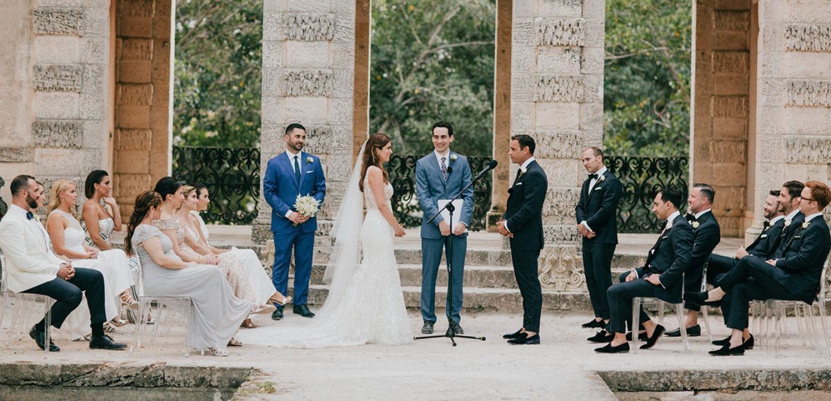 Couple and wedding party at outdoor altar. 