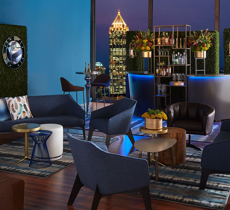 Cocktail reception with blue soft seating and bar with blue light