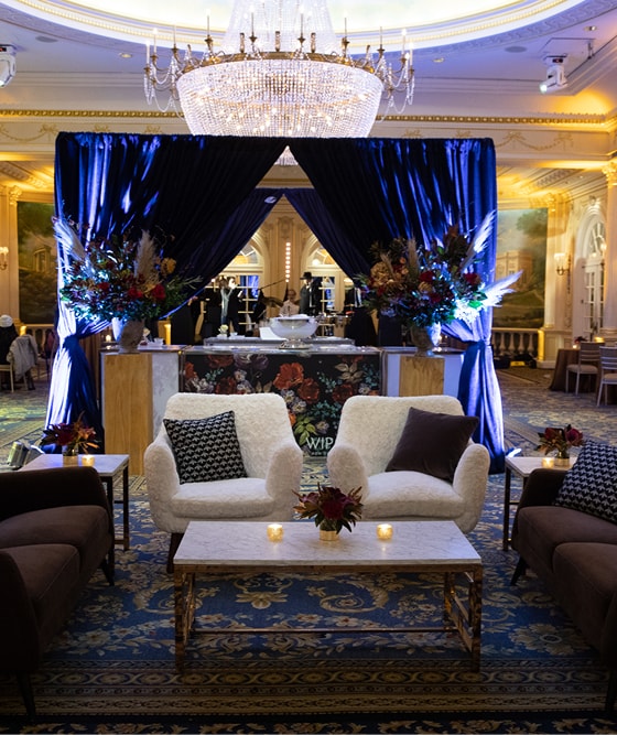 event in elegant ballroom featuring bar area with blue drape and lounge with brown and white seating