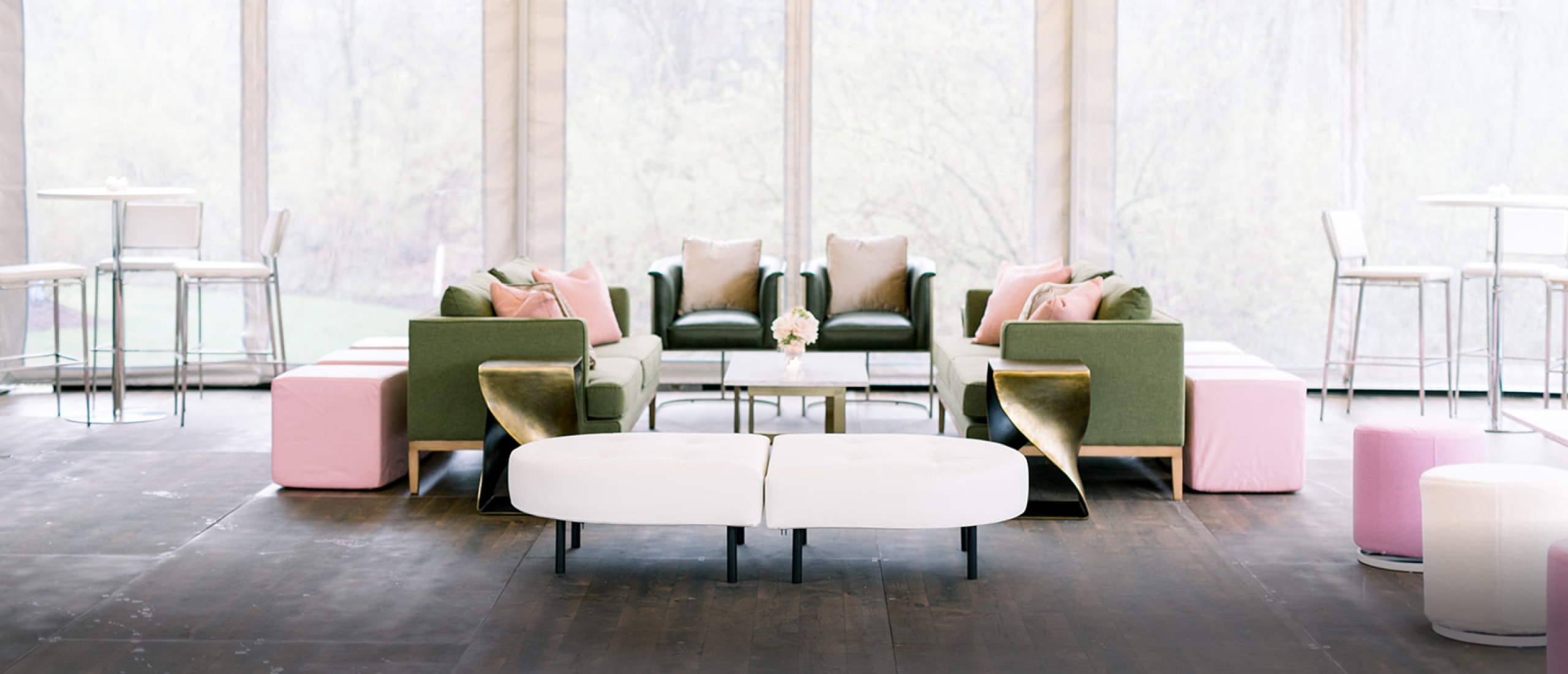 green seating with pink and gold decor at wedding reception in outdoor tent