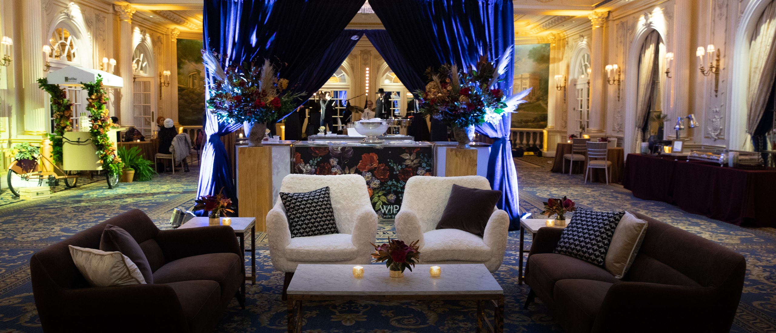 event in elegant ballroom featuring bar area with blue drape and lounge with brown and white seating