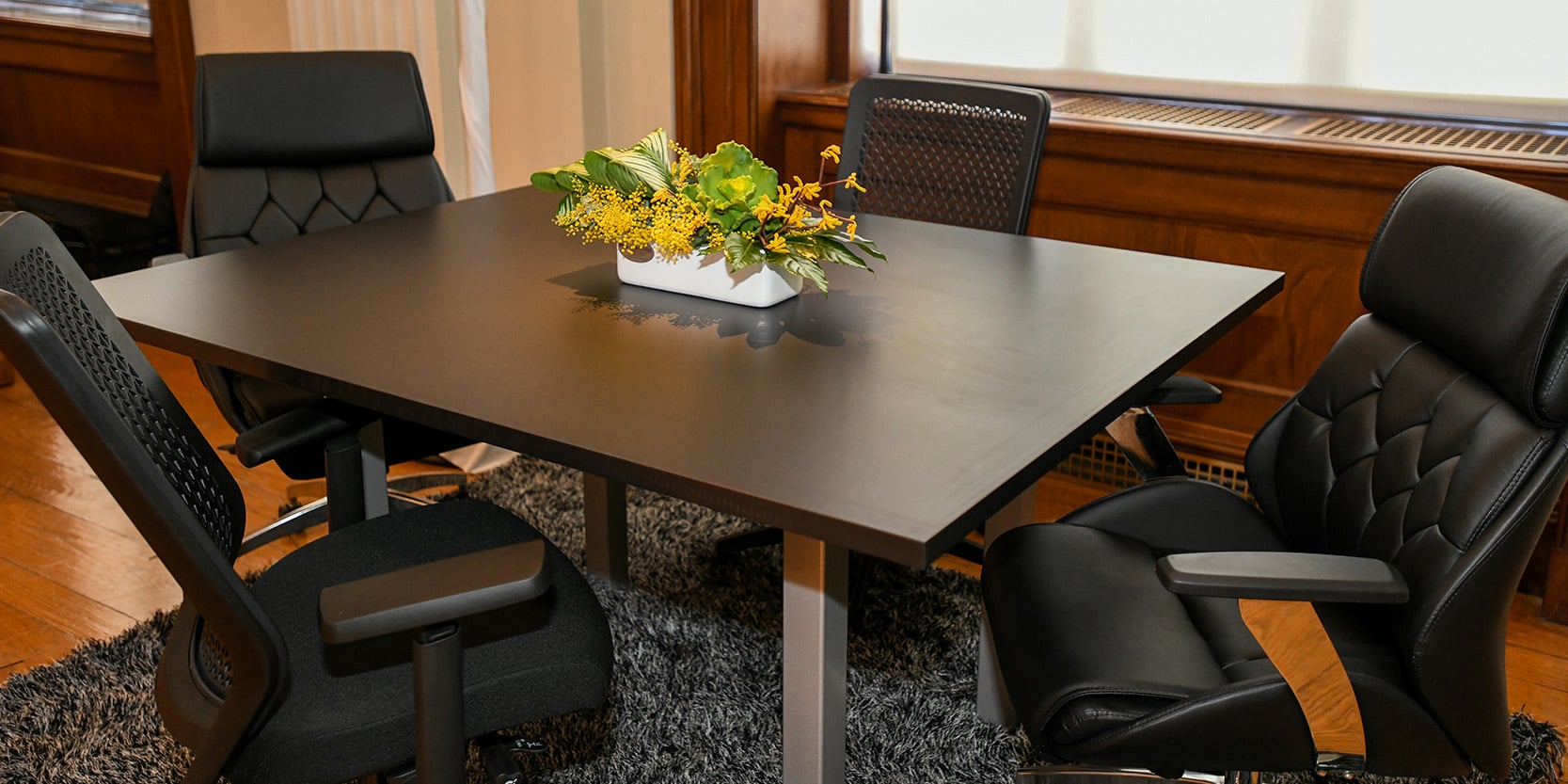 large trade show booth with drape dividers, brown leather seating and orange bench ottomans